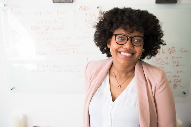 An engineer smiling in front of a whiteboard covered in architecture notes