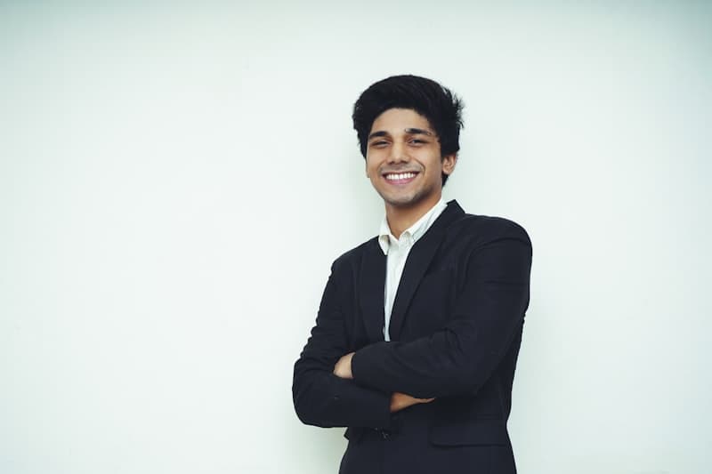 A smiling professional in a dark suit jacket, arms folded
